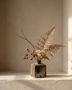 Square Terracotta Vase with mottled dark and rust glaze, holding dried fern and branches on a plaster ledge