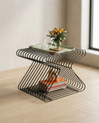 Geometric Side Table, an S-curved bent black wire frame holding a tray, on pale oak flooring