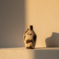 Ceramic vase with irregular black brushwork on a plaster ledge