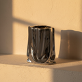 Crumpled paper bag vase in mirror chrome on a plaster ledge