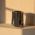 Crumpled paper bag vase in mirror chrome on a plaster ledge