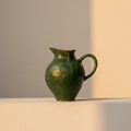 Deep green glazed pitcher with a pulled spout and looped handle