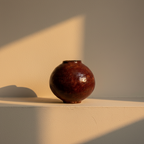 Round moon jar under a deep glossy oxblood glaze