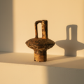 Scorched stoneware vase with a large squared handle on a plaster ledge