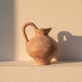 Small terracotta jug vase with a looped handle and curved neck