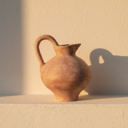 Small terracotta jug vase with a looped handle and curved neck