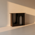 Matte black arch console table against a plaster wall