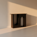 Matte black arch console table against a plaster wall