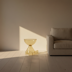 The amber acrylic side table beside a sofa, glowing in low sun at room scale