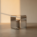 Mirror chrome C-shaped side table in an empty plaster room