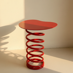 Red side table balanced on an open coiled steel spring base