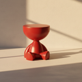 Glossy red sculptural side table on three stubby feet