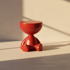 Glossy red sculptural side table on three stubby feet