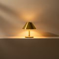 Brass cordless mushroom lamp lit on a plaster ledge