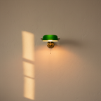 Green glass wall lamp on a brass swing arm, lit