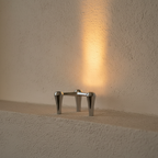 Miniature chrome tripod uplight casting a beam up the wall