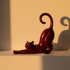 Glossy red abstract cat figure on a plaster ledge