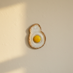 Ceramic fried egg wall ornament mounted on plaster