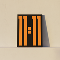 Orange bars on a black ground, unframed canvas leaning on plaster