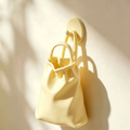 Cream wall-mounted vase shaped like a slouching handbag