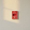 Red fire alarm style light switch cover on a plaster wall