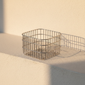 Open square wire storage basket on warm plaster