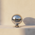 Mirror-polished chrome sphere storage jar on a plaster ledge