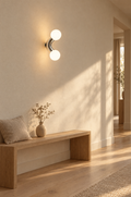 Two-arm chrome wall light glowing in a quiet hallway